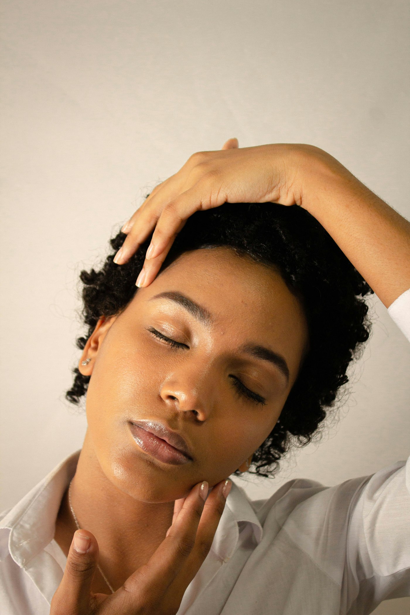 Latina woman in a soft white shirt, eyes closed, restful.
